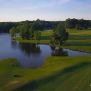 Golf course green with pond and trees